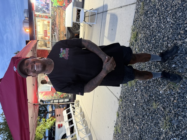 Alex Vazquez in a red CoquiEats shirt standing in front of the CoquiEats food truck