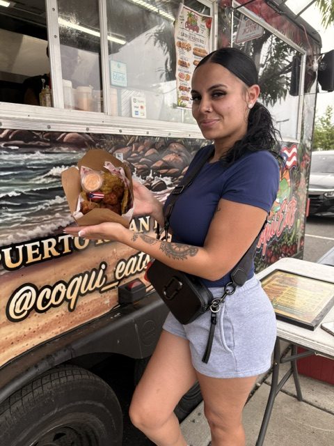 A customer showing her CoquiEats meal beside the truck