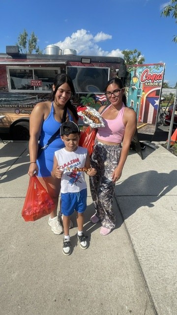 A family sharing CoquiEats food in front of the truck