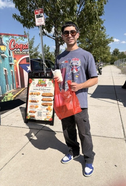 Guest holding a CoquiEats order beside the truck menu board