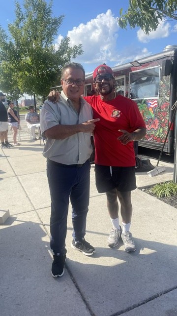 Two guests posing together in front of the CoquiEats food truck