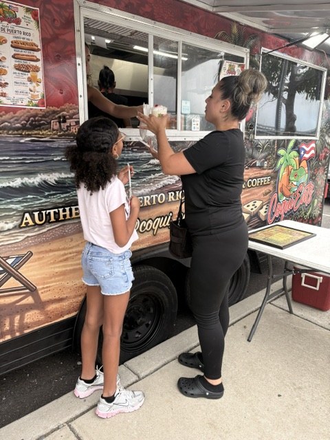 A guest and child picking up an order at the CoquiEats window