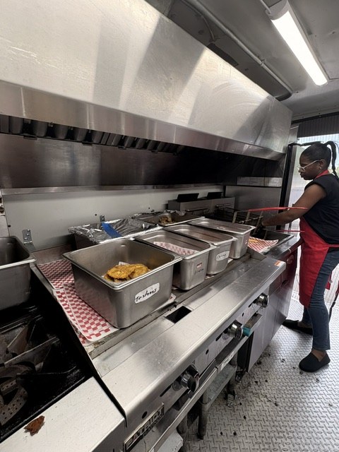 Cook working the fryer line inside the CoquiEats food truck kitchen